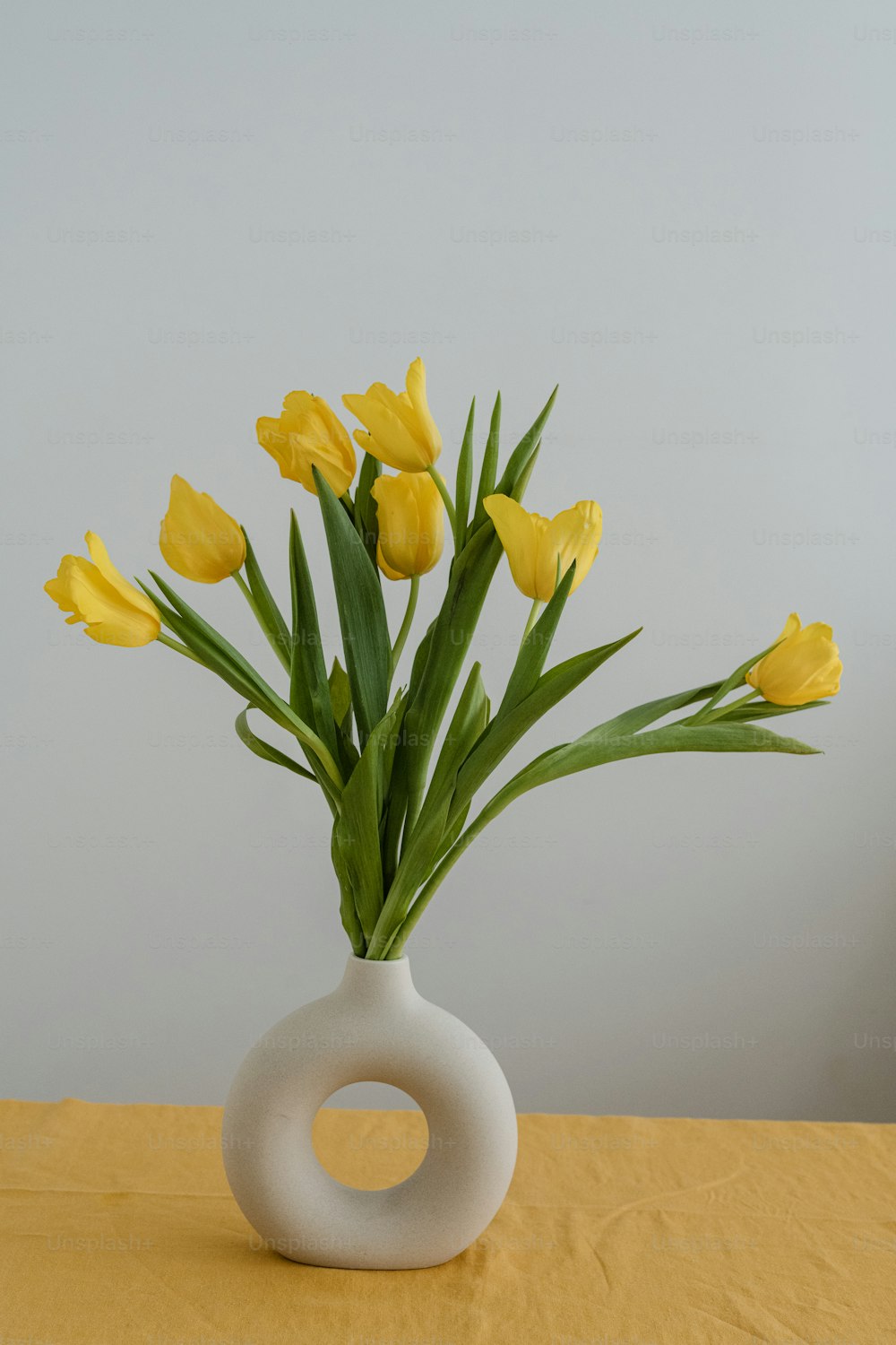テーブルの上に黄色い花でいっ��ぱいの花瓶