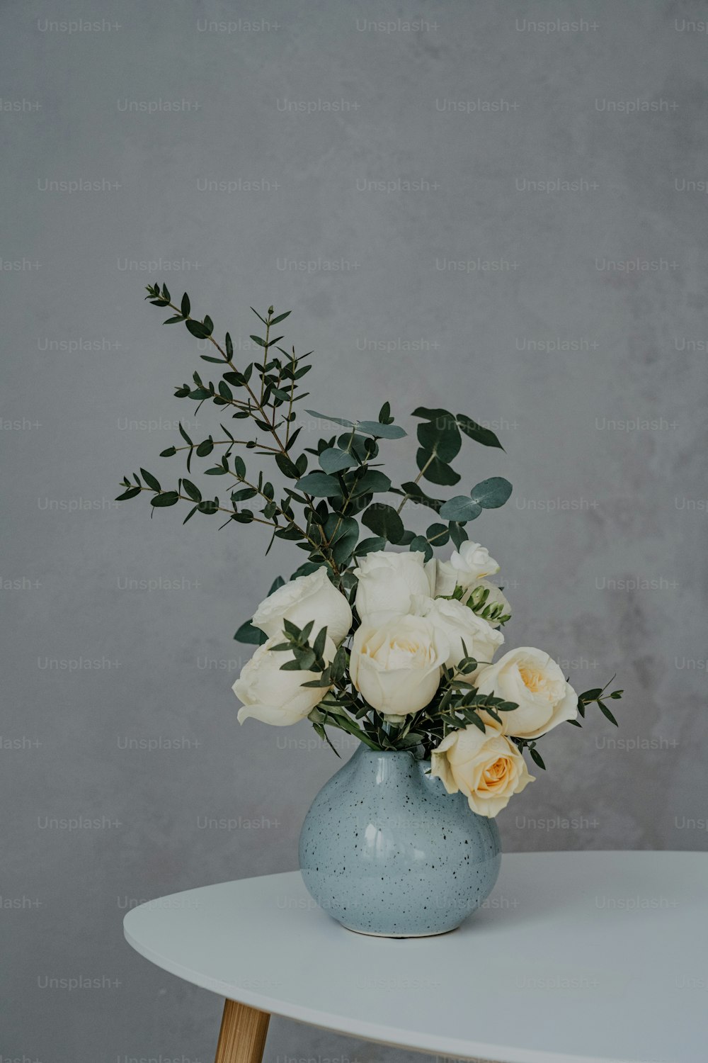 Un jarrón azul lleno de flores blancas encima de una mesa