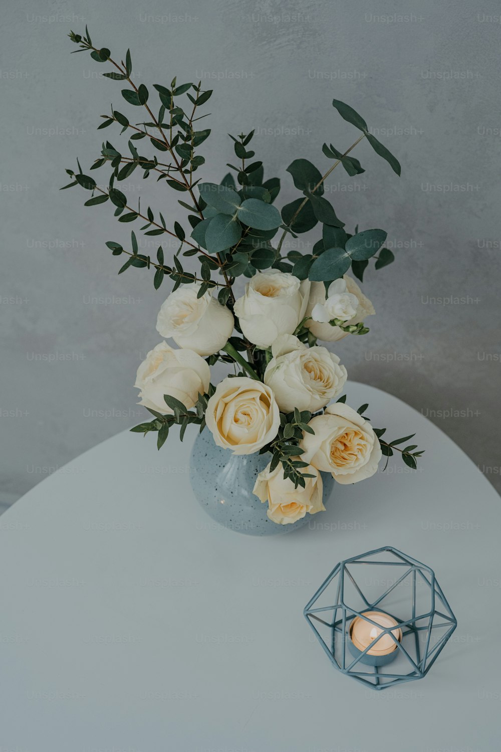 um vaso com flores e uma vela em uma mesa