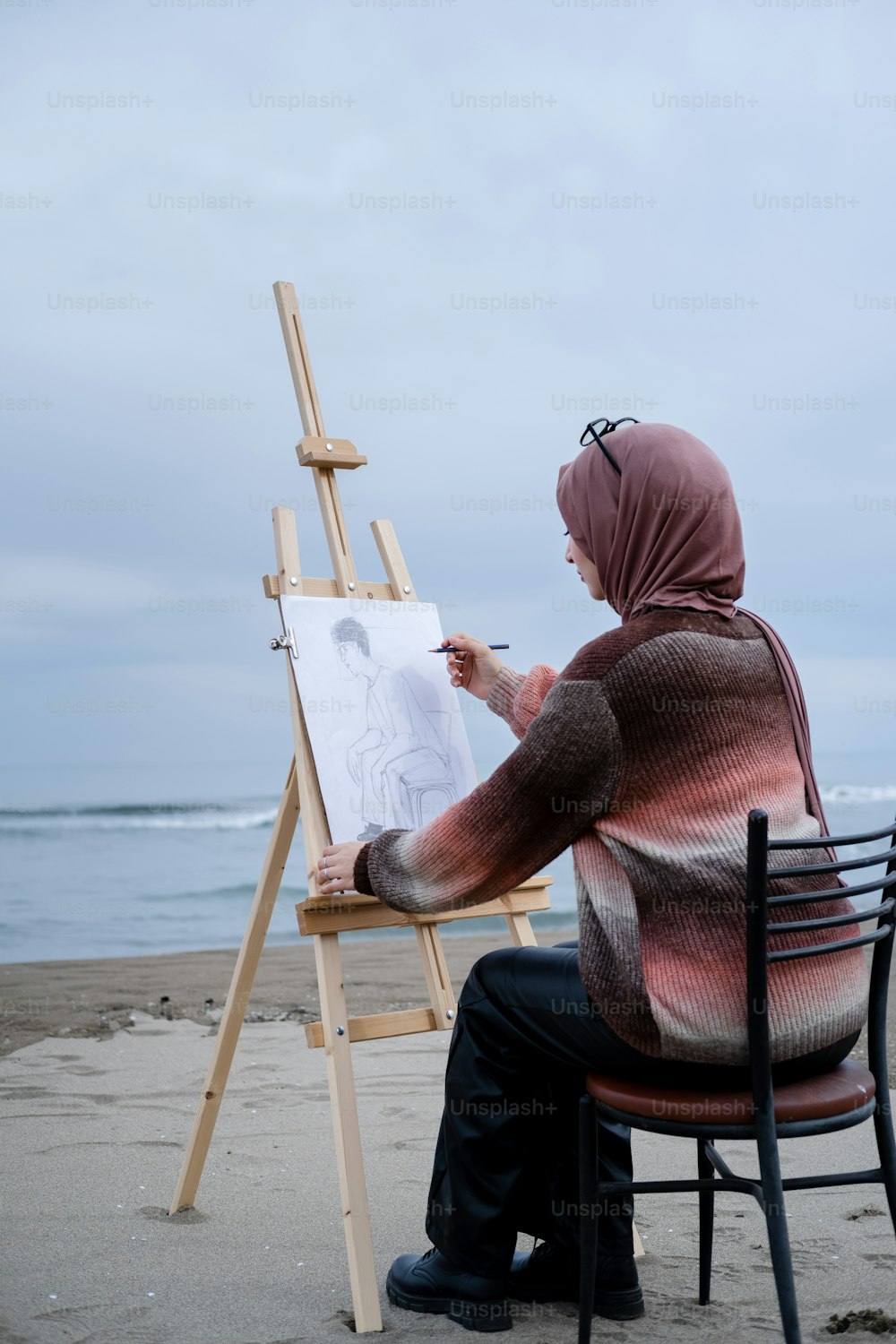 a person sitting in a chair drawing on a canvas