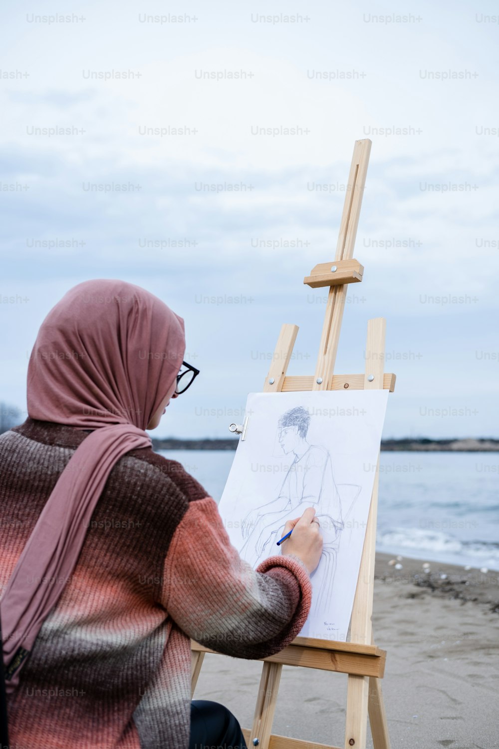 ヒジャーブを着た女性がイーゼルに絵を描いている