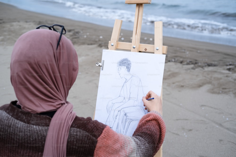 a woman is drawing a picture on a easel