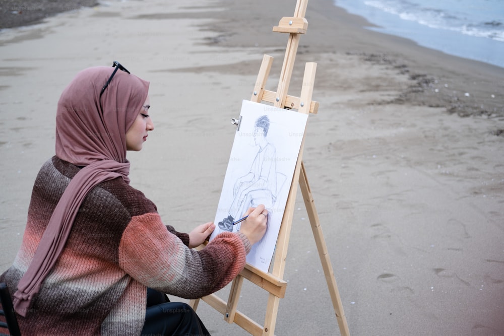 Una mujer con hiyab está dibujando en un caballete