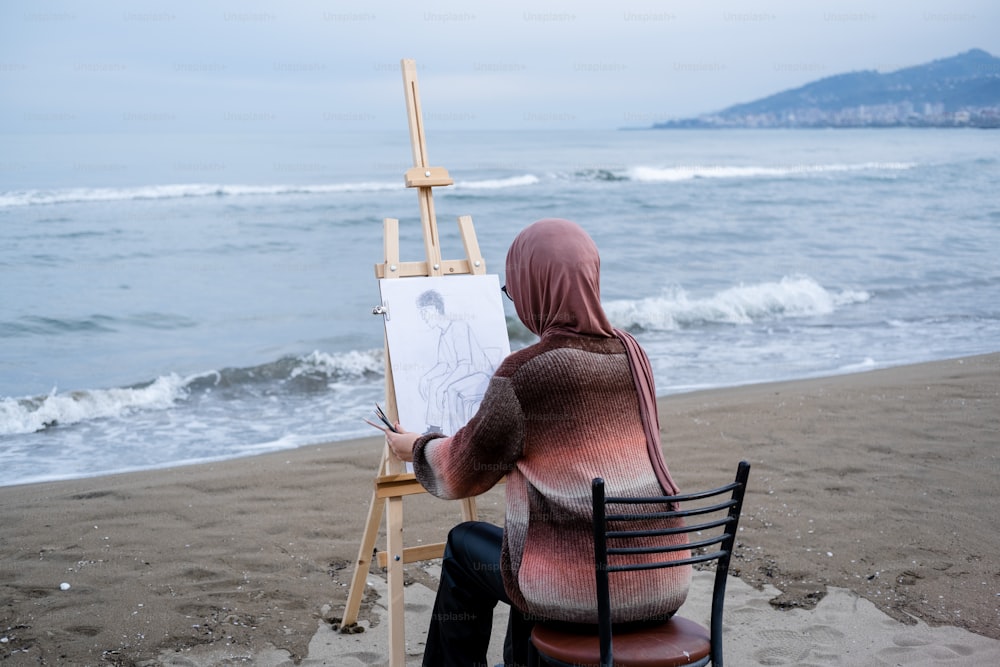 Eine Person, die in einem Stuhl sitzt und am Strand malt