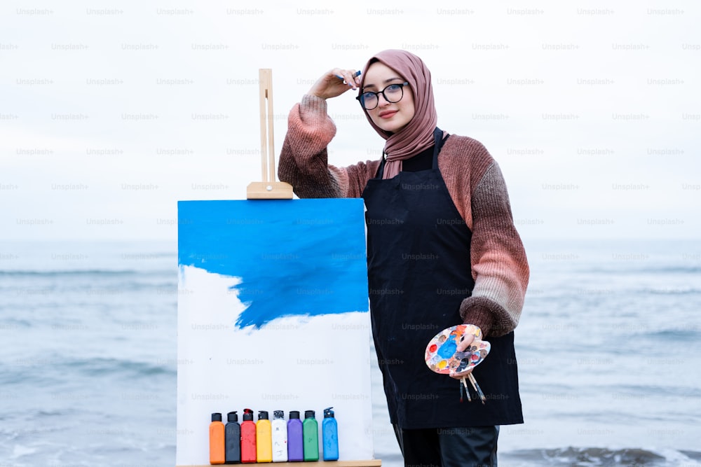 a woman standing next to an easel with a painting on it