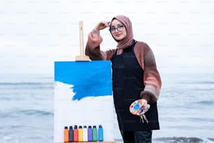 a woman standing next to an easel with a painting on it