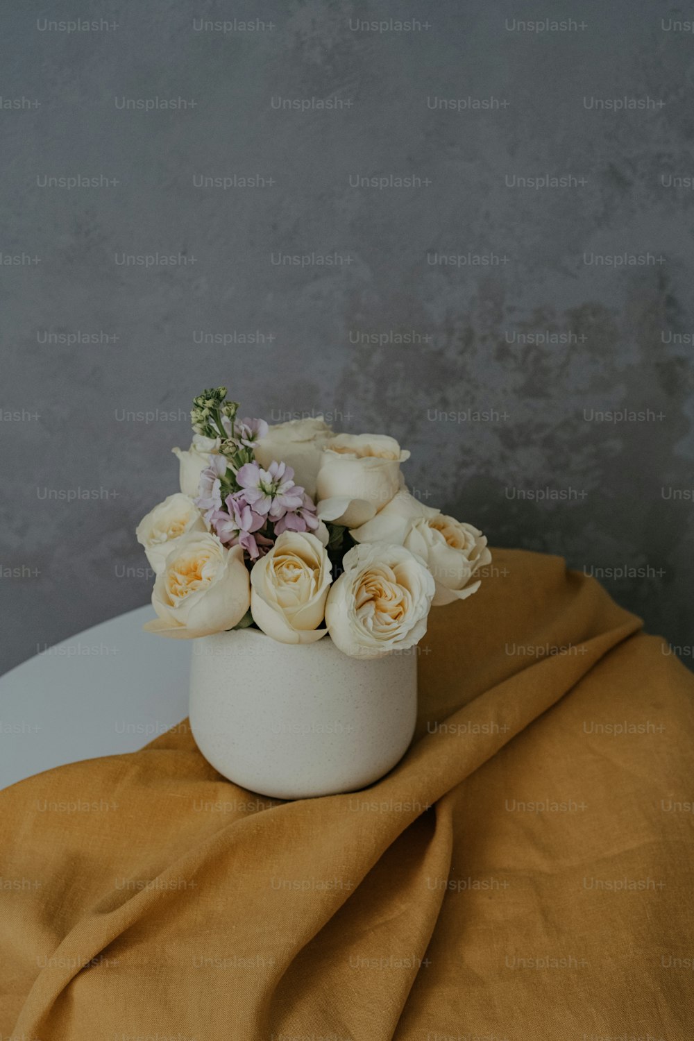 Un jarrón blanco lleno de flores blancas encima de una mesa