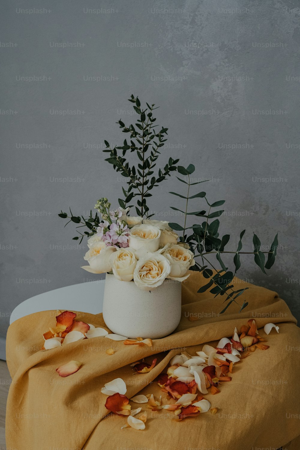 a white vase with flowers on a table