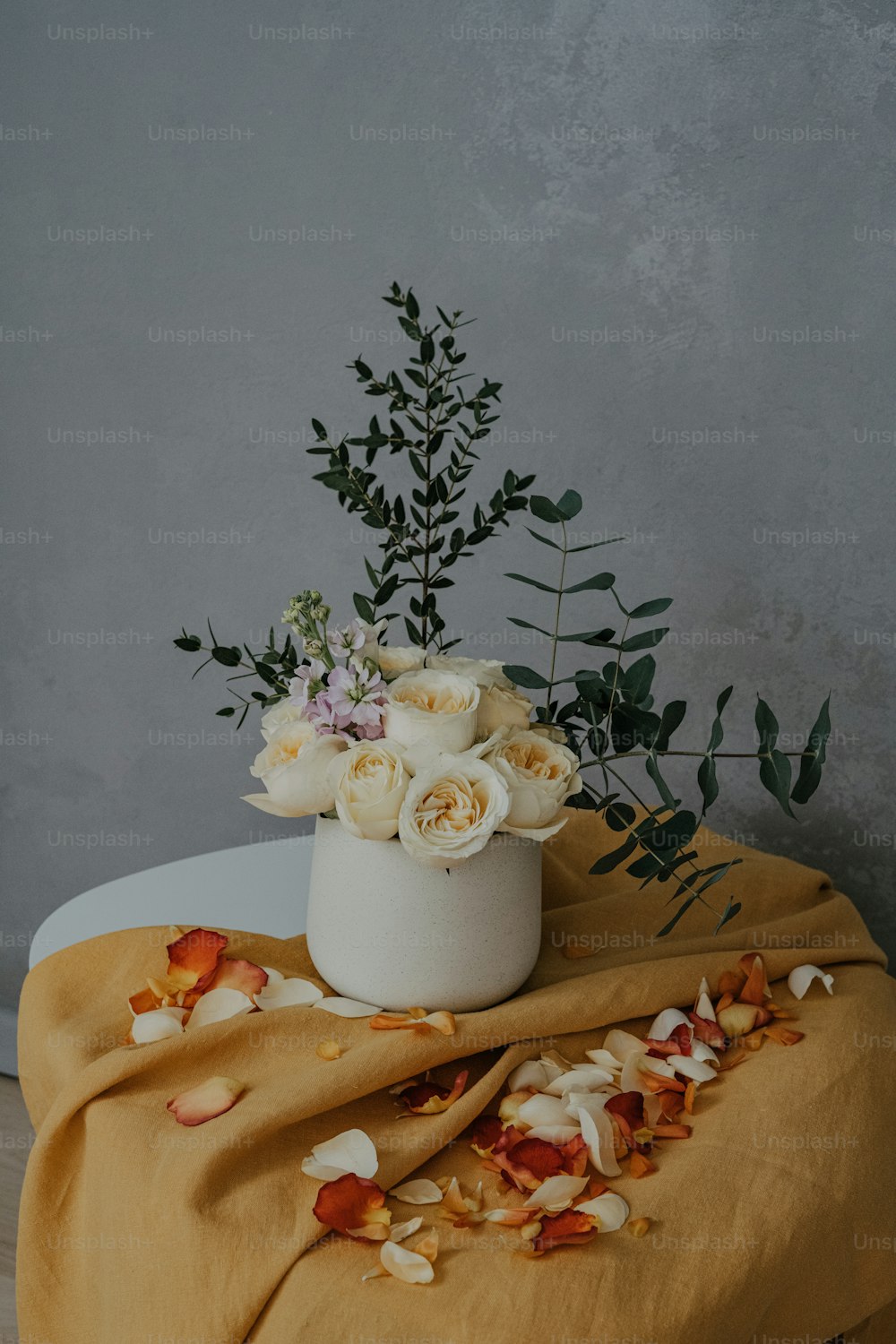 eine weiße Vase mit Blumen auf einem Tisch