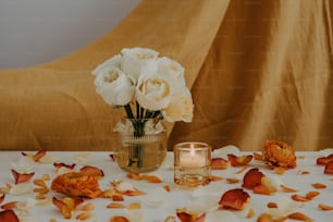 um vaso de flores em uma mesa com uma vela