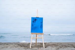a blue easel sitting on top of a sandy beach