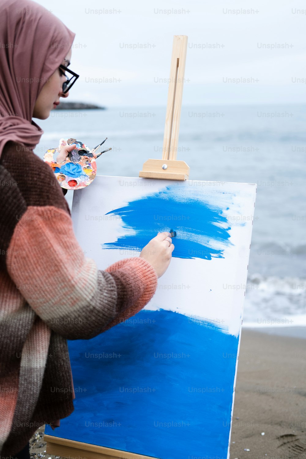 Eine Frau im Hijab malt ein Bild auf eine Leinwand