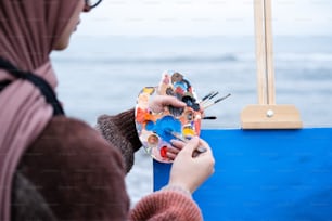 a woman is painting a picture on a easel