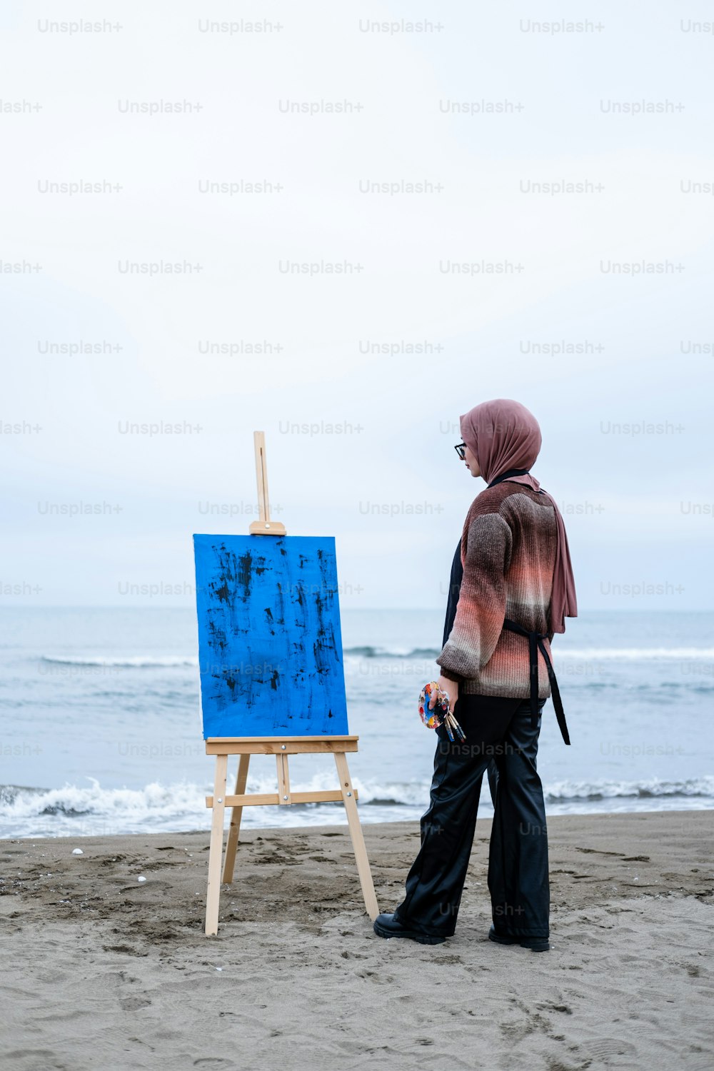 a person standing in front of an easel on a beach