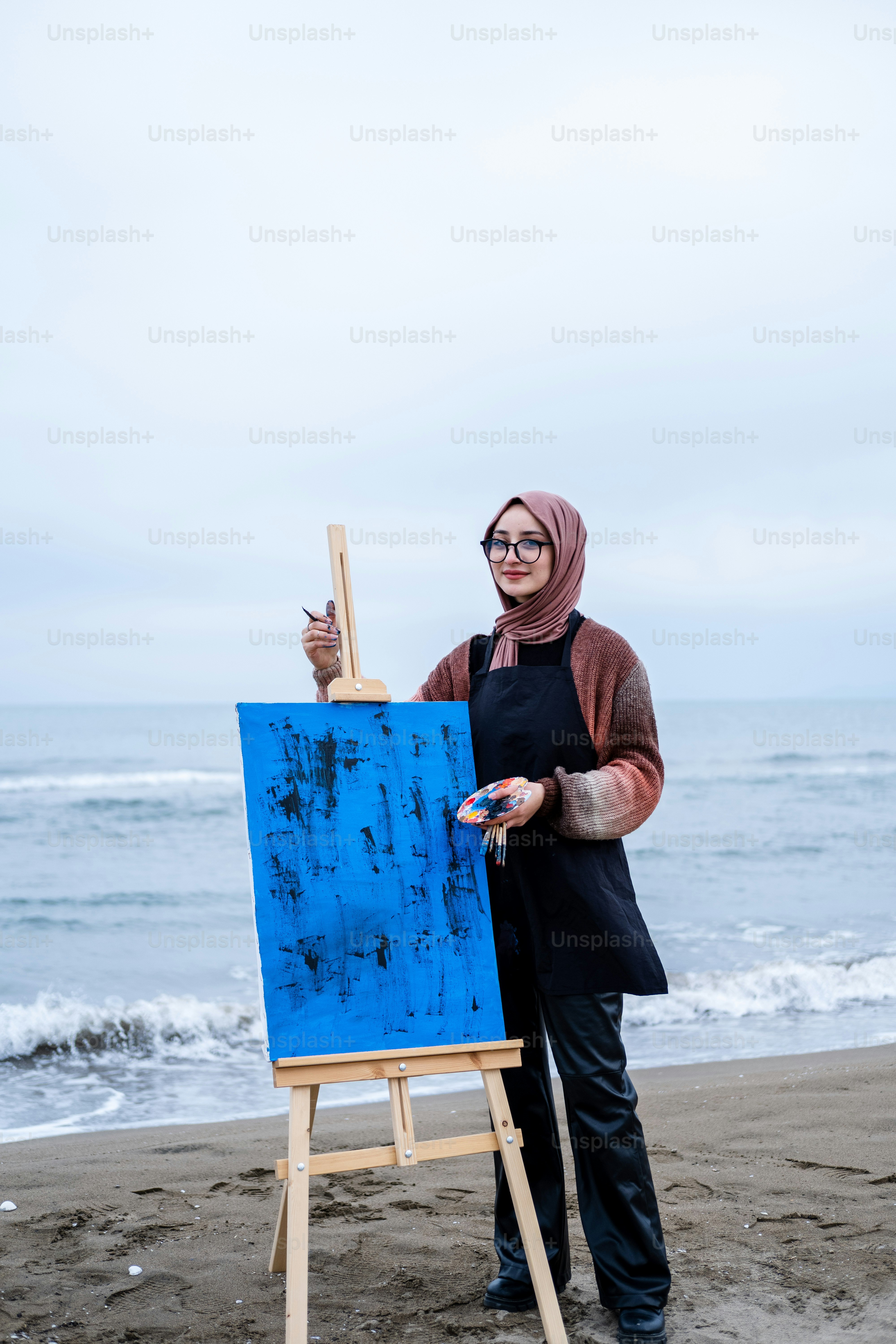 A woman standing on a beach next to an easel photo – Standing Image on ...