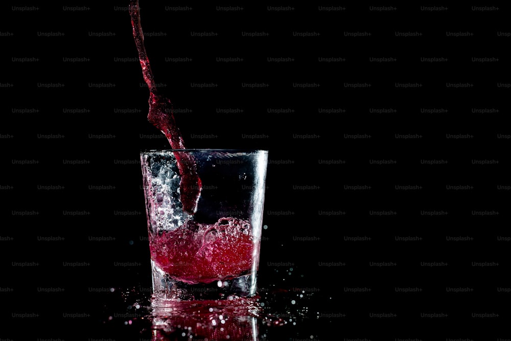 un vaso lleno de líquido rojo encima de una mesa