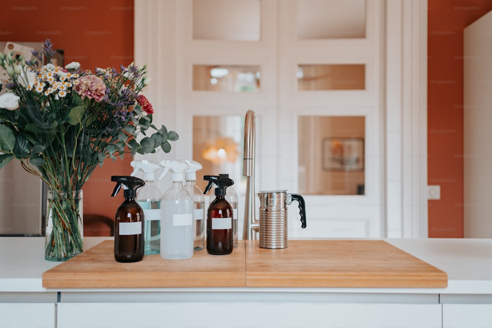 a wooden counter topped with bottles and a vase filled with flowers