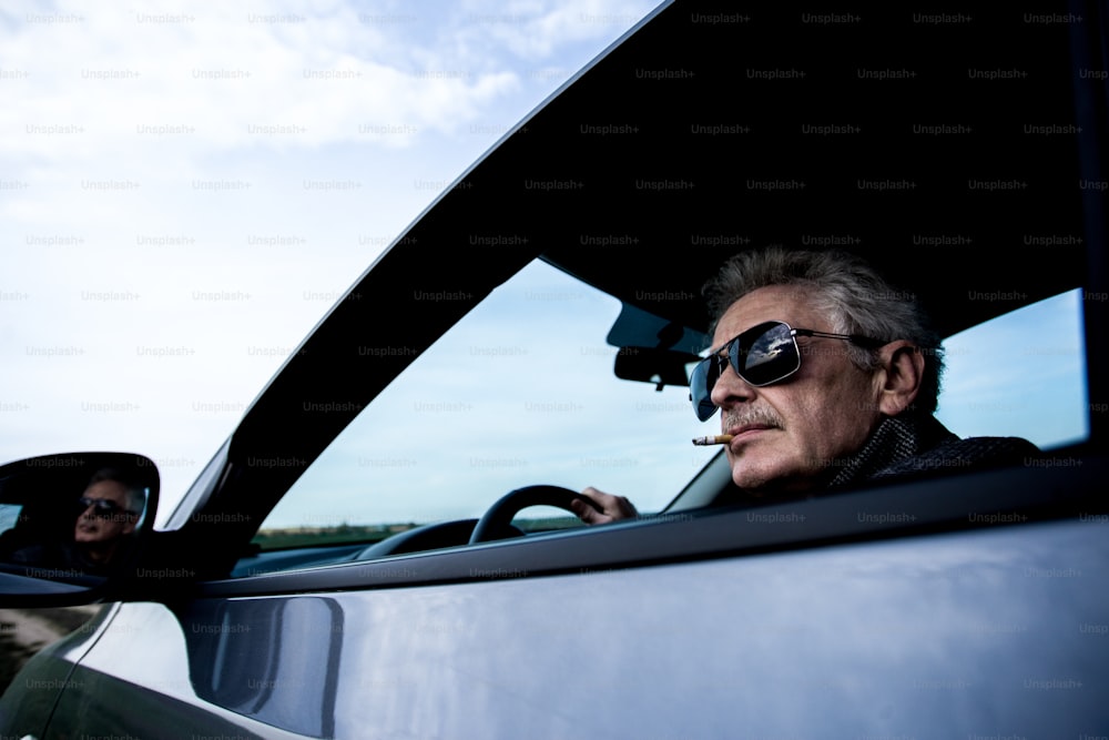 a man sitting in a car with a cigarette in his mouth