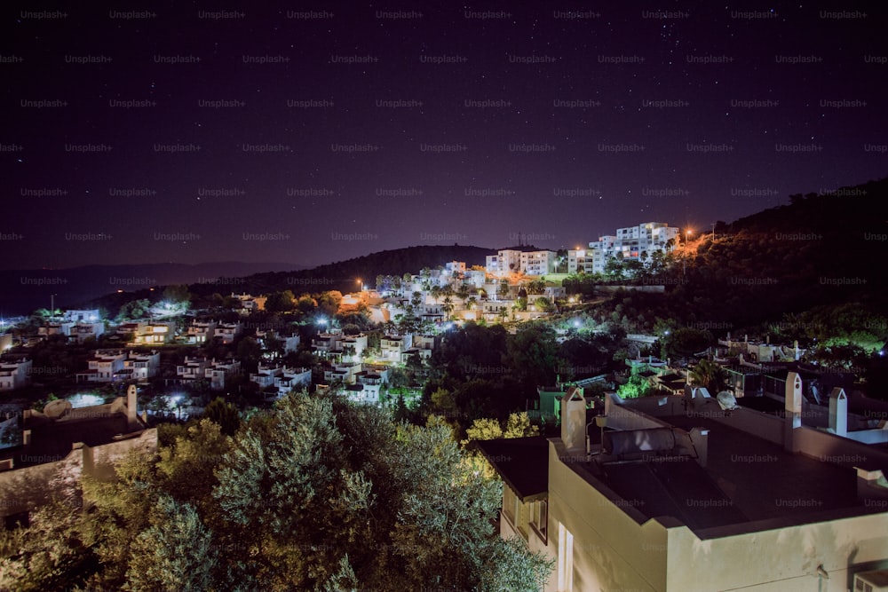 Una vista nocturna de una ciudad con una colina al fondo