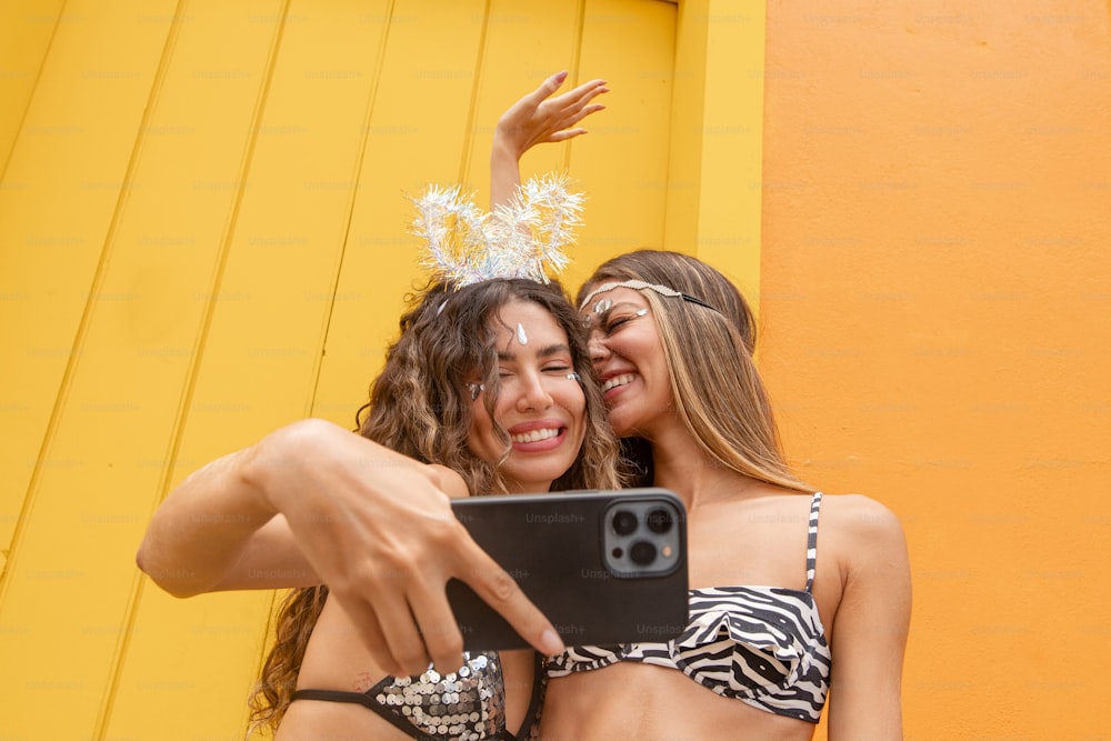 Due donne che scattano un selfie davanti a un muro giallo