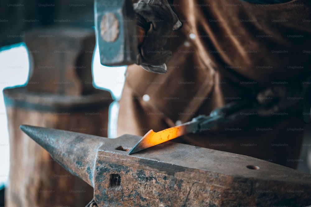 um homem trabalhando em um pedaço de metal com um martelo