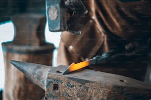 Ein Mann arbeitet mit einem Hammer an einem Stück Metall