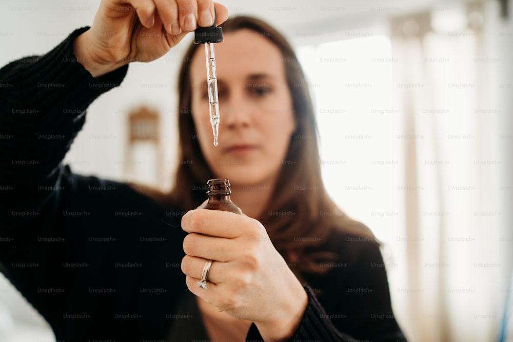 a woman holding a bottle with a needle in it