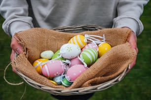 une personne tenant un panier rempli d’œufs de Pâques