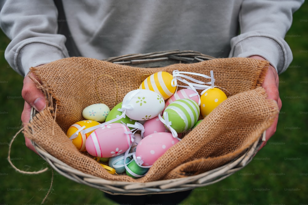 a person holding a basket filled with easter eggs