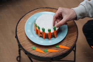Eine Person, die einen Karottenkuchen auf einem Tisch dekoriert