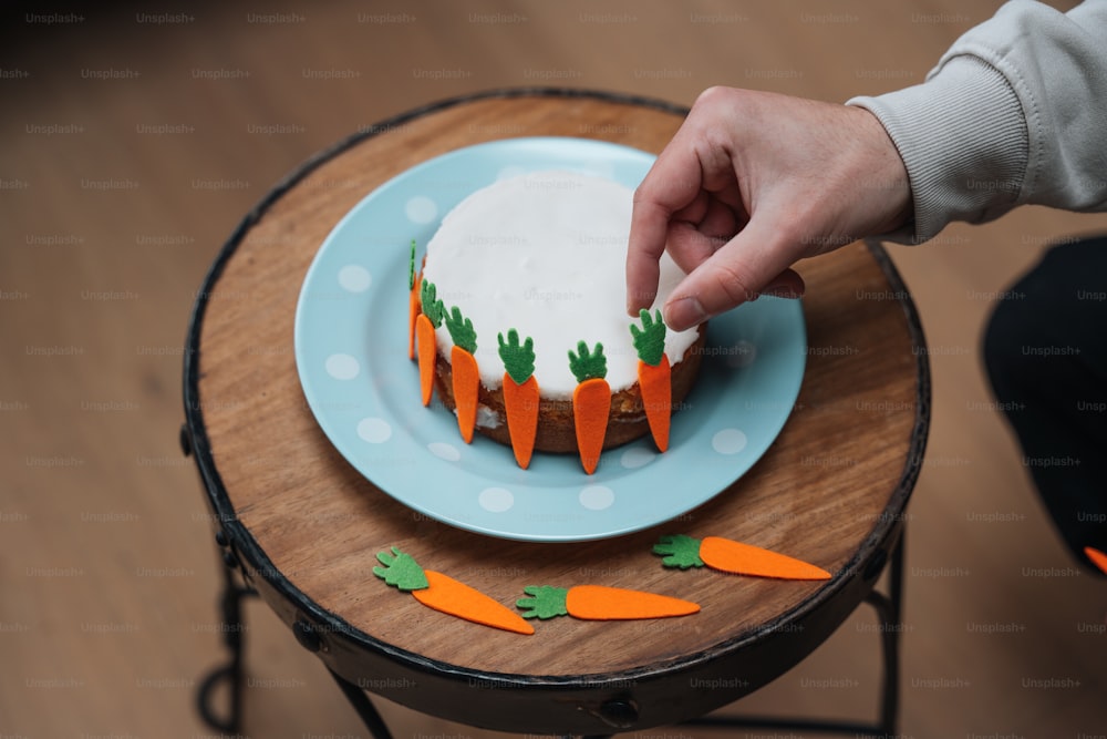 Eine Person, die einen Karottenkuchen auf einem Tisch dekoriert