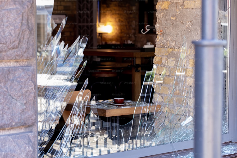 a broken glass window with a table and chairs in it