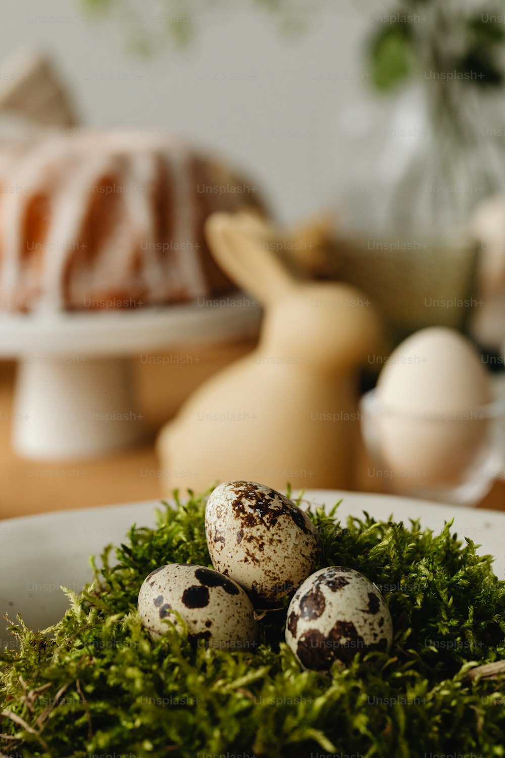 three quail eggs in a bowl of moss on a table