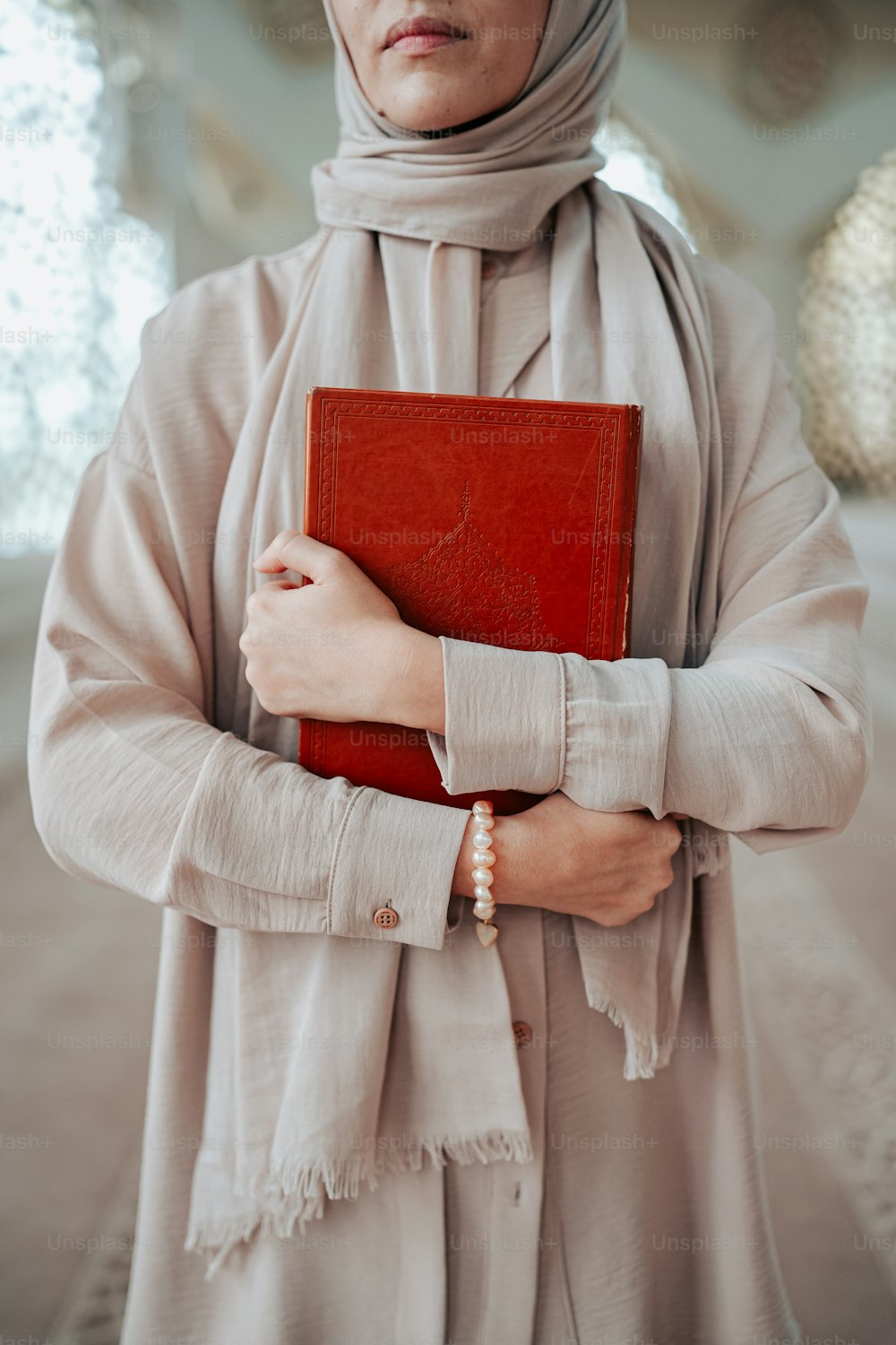 a woman in a hijab holding a red book
