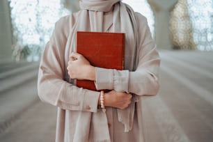 a woman in a hijab holding a red book