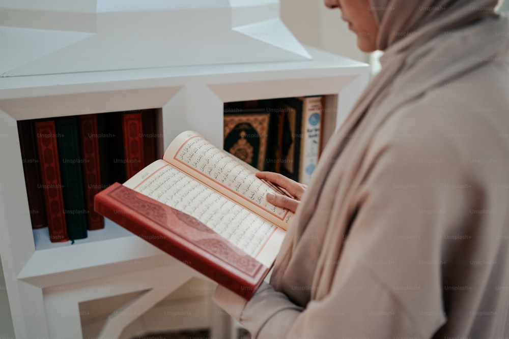 uma mulher em um hijab está segurando um livro