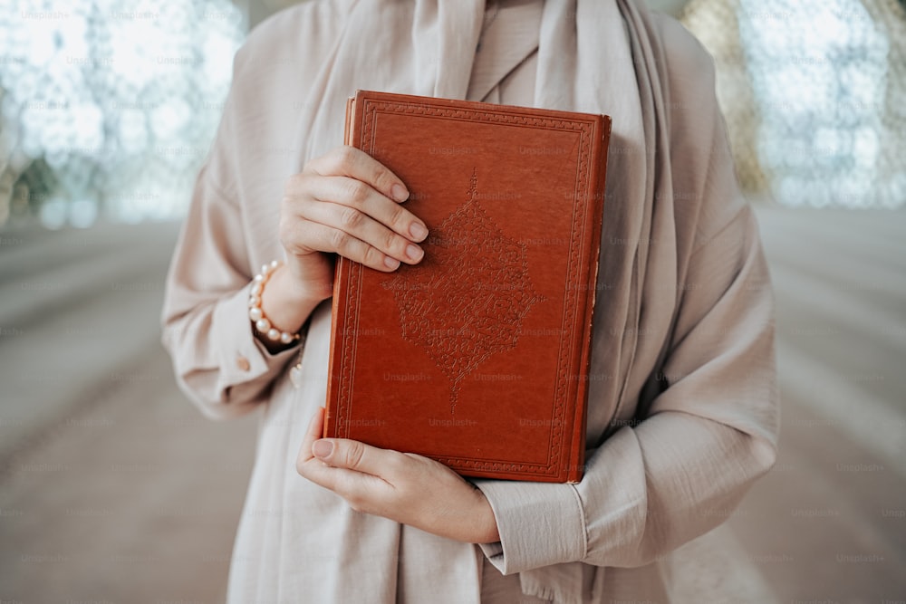 uma mulher segurando um livro marrom em suas mãos