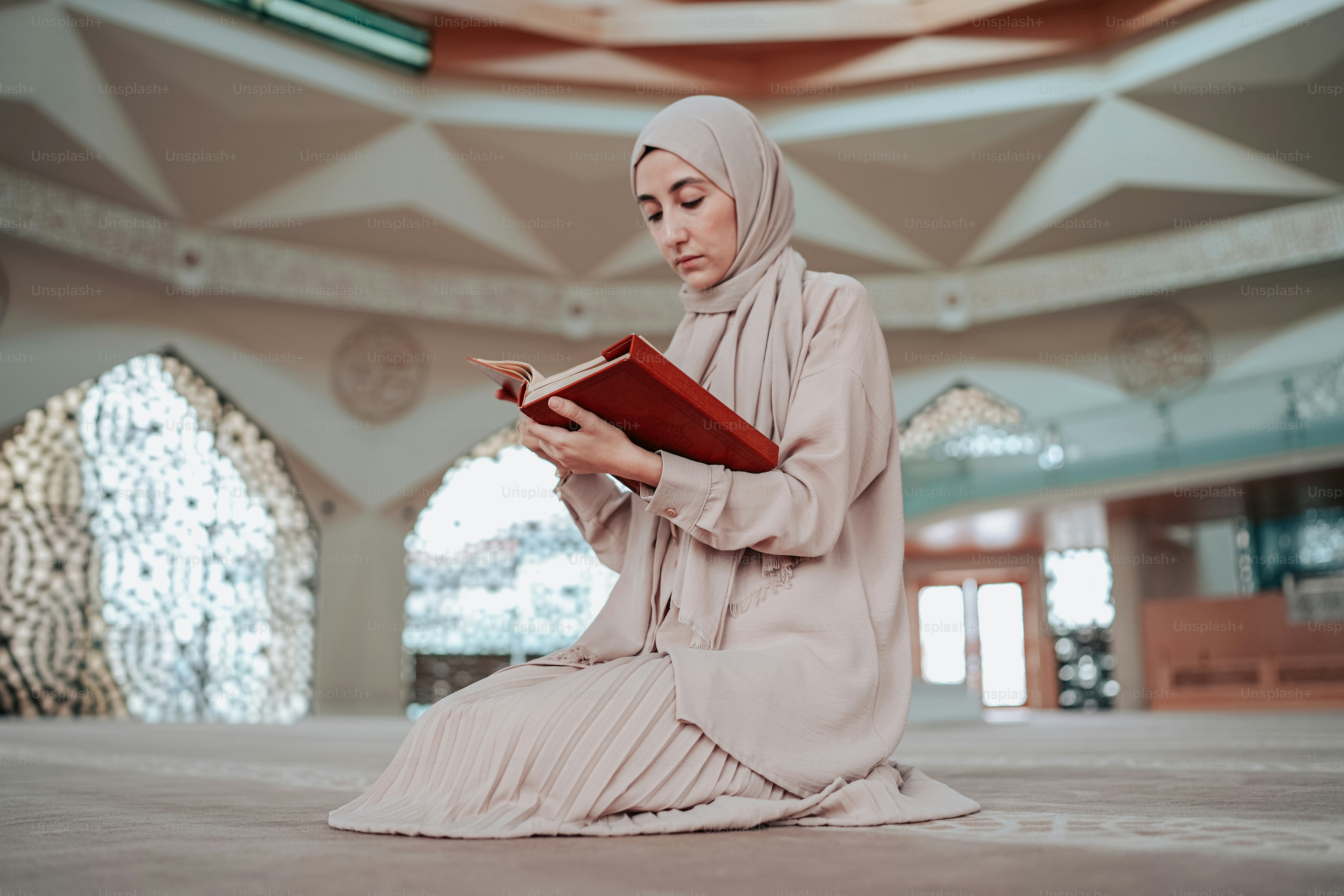 A woman sitting on the floor reading a book photo – Praying Image on ...