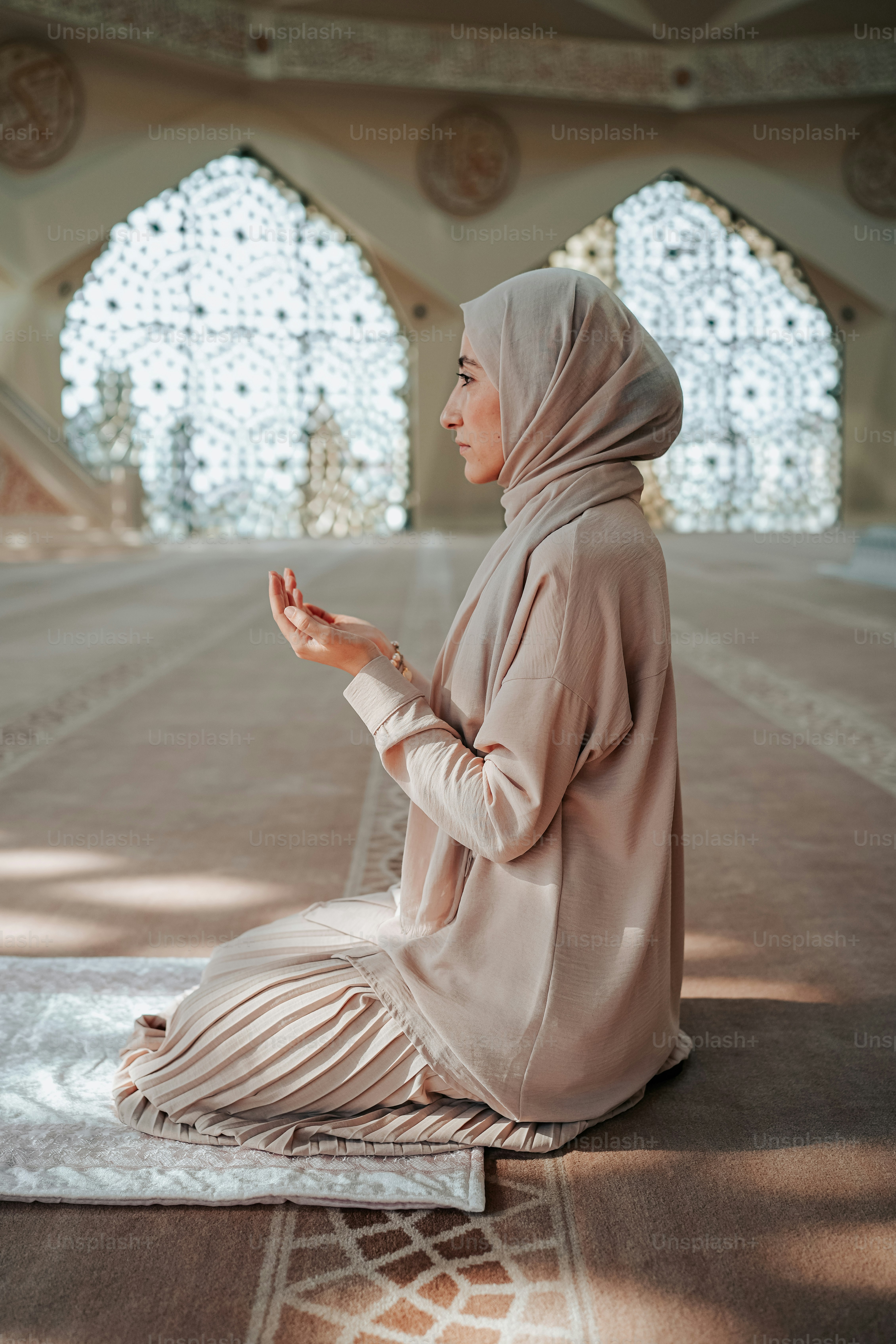 seorang wanita berjilbab duduk di atas karpet