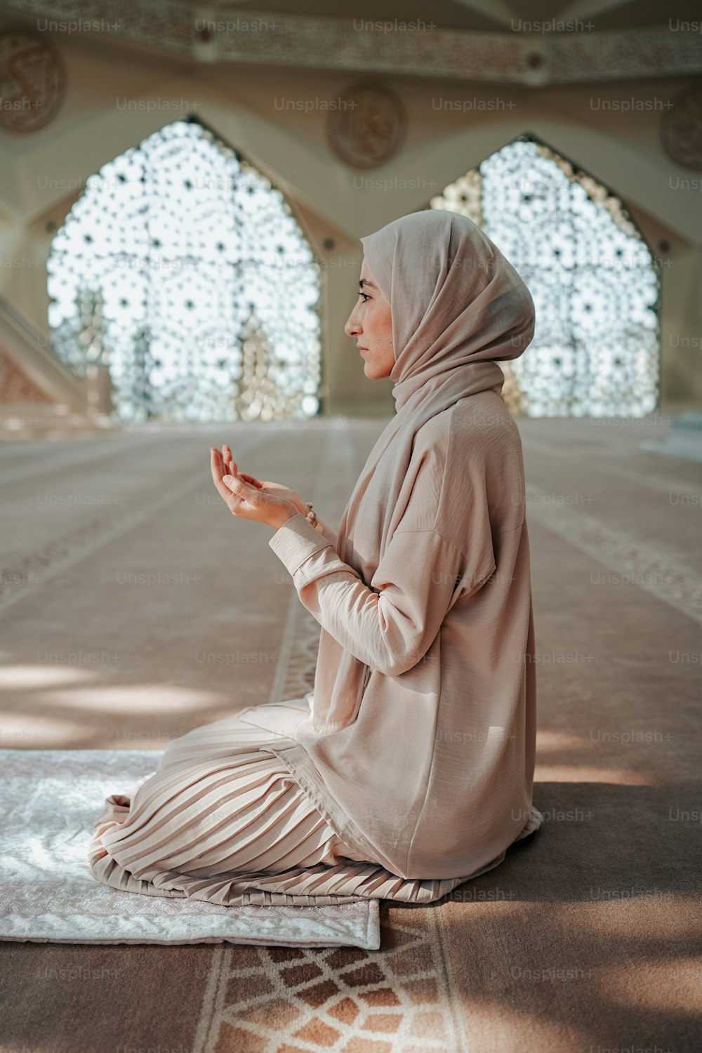 Eine Frau im Hijab sitzt auf einem Teppich