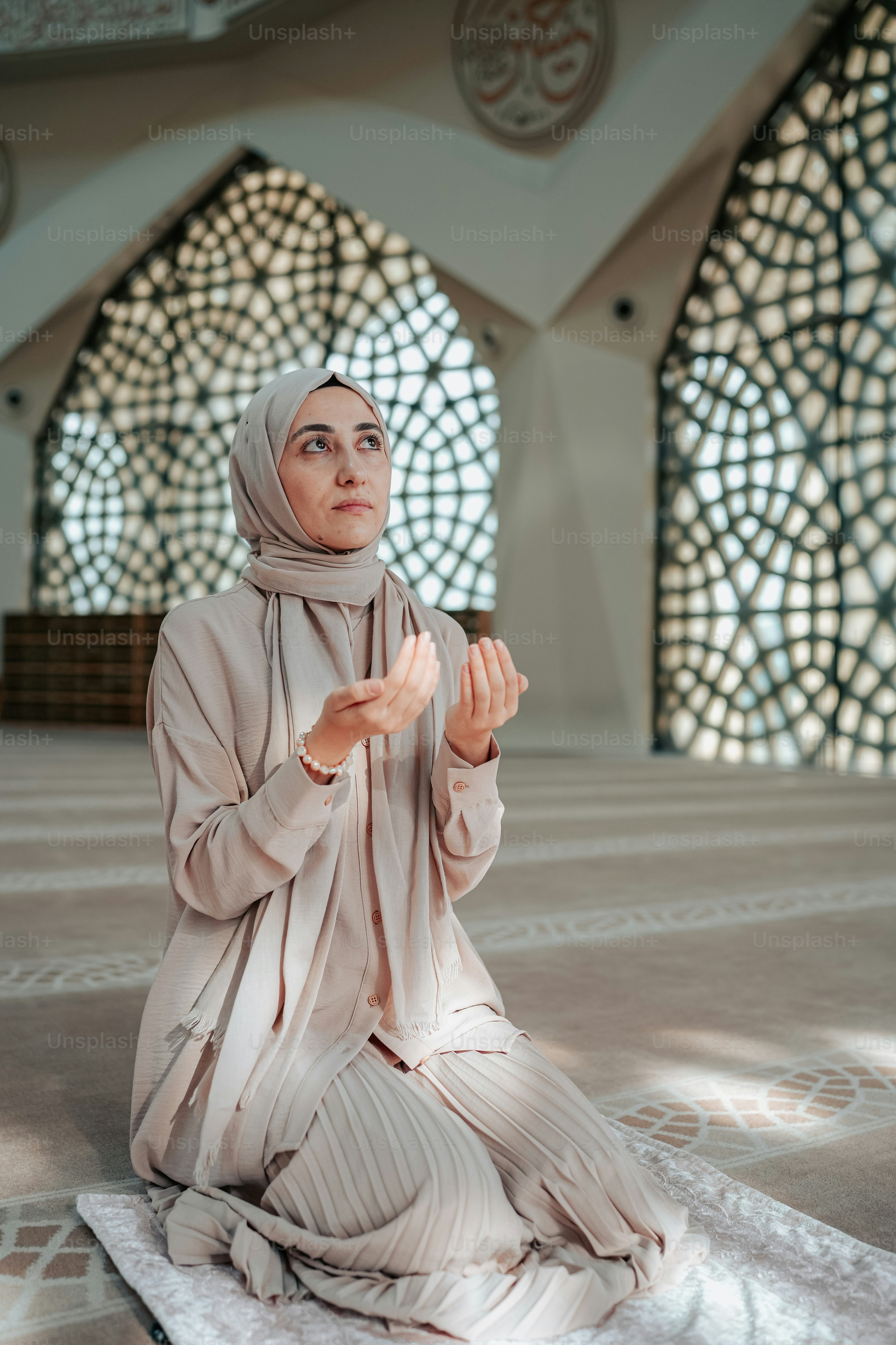 A woman in a hijab sitting on the floor photo – Woman looking up Image ...