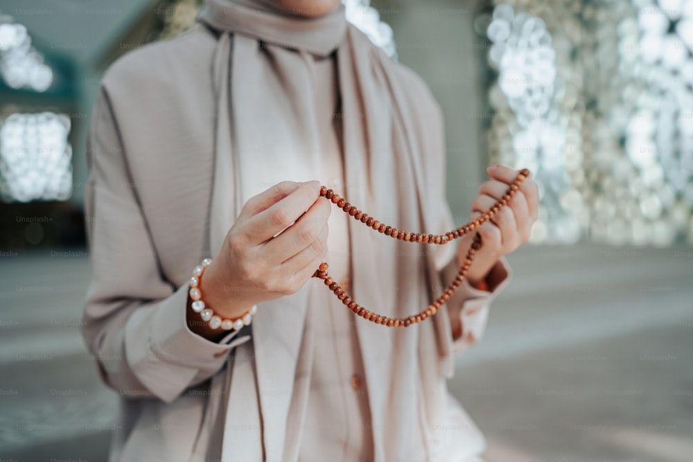 Una mujer con hiyab sosteniendo un rosario