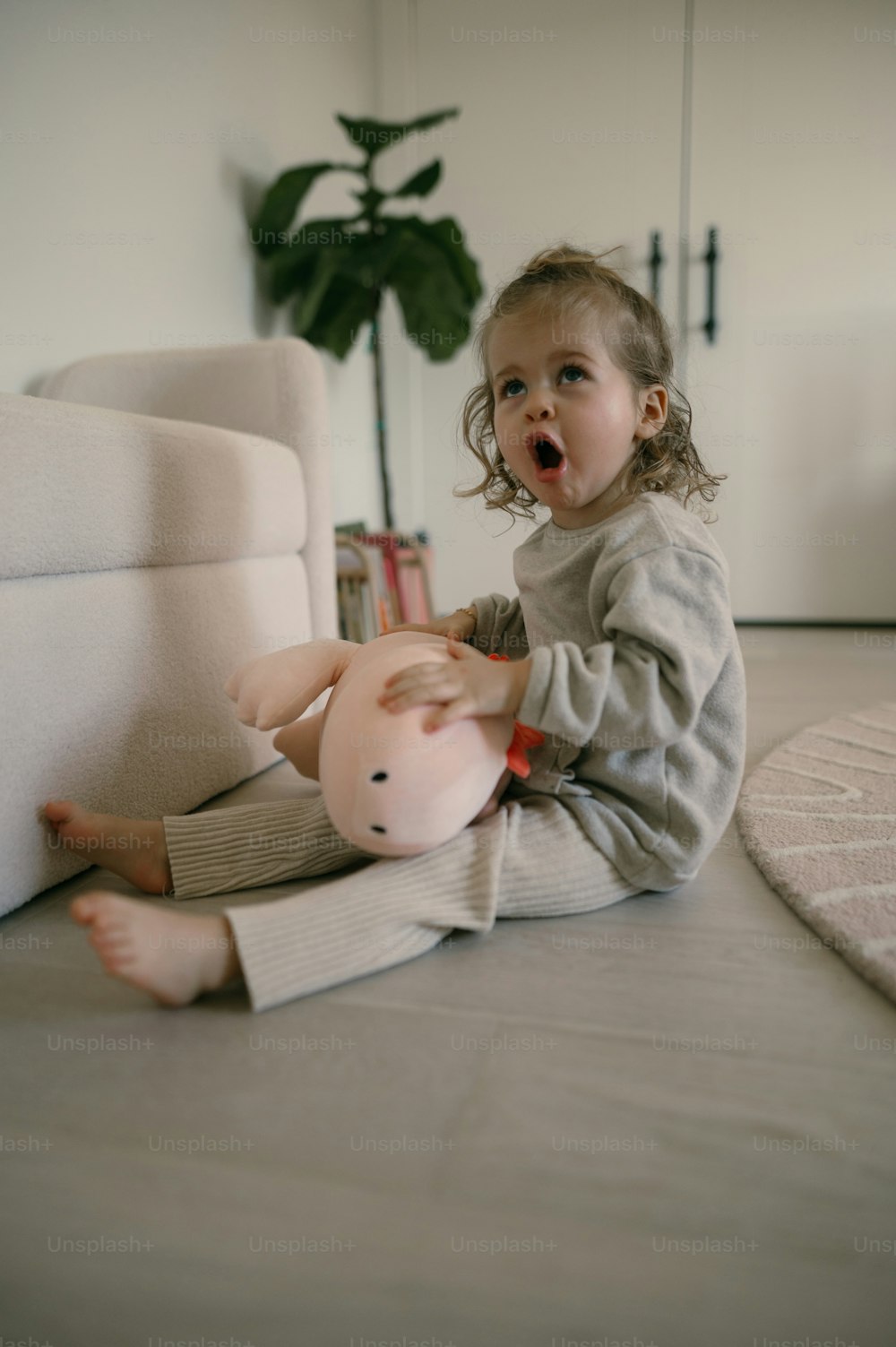 a little girl sitting on the floor playing with a pig