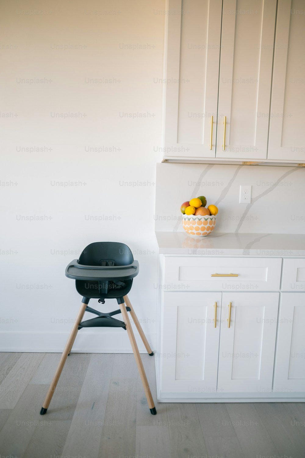 a black chair sitting in a kitchen next to a bowl of fruit