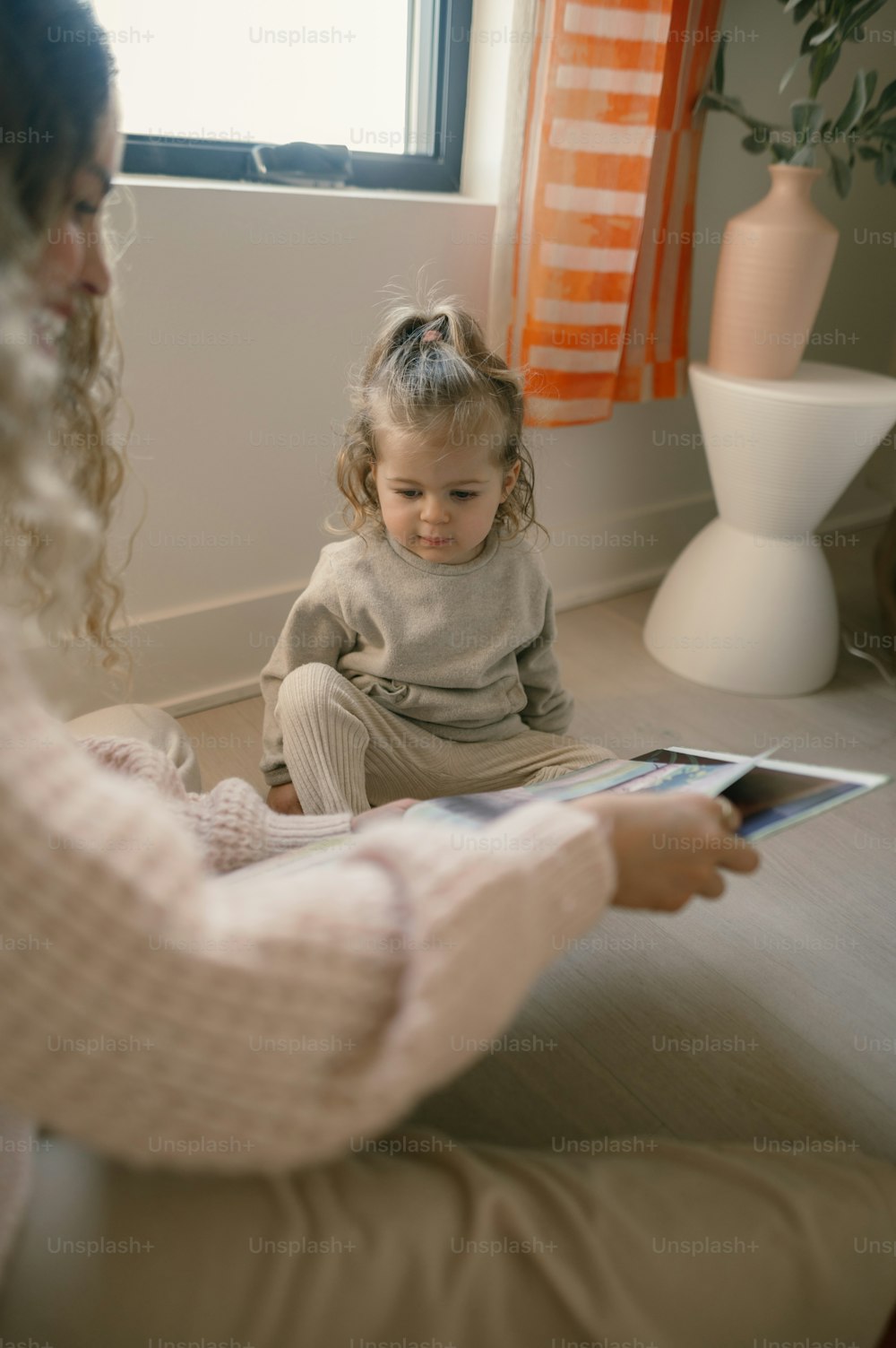 a little girl sitting on the floor with a tablet