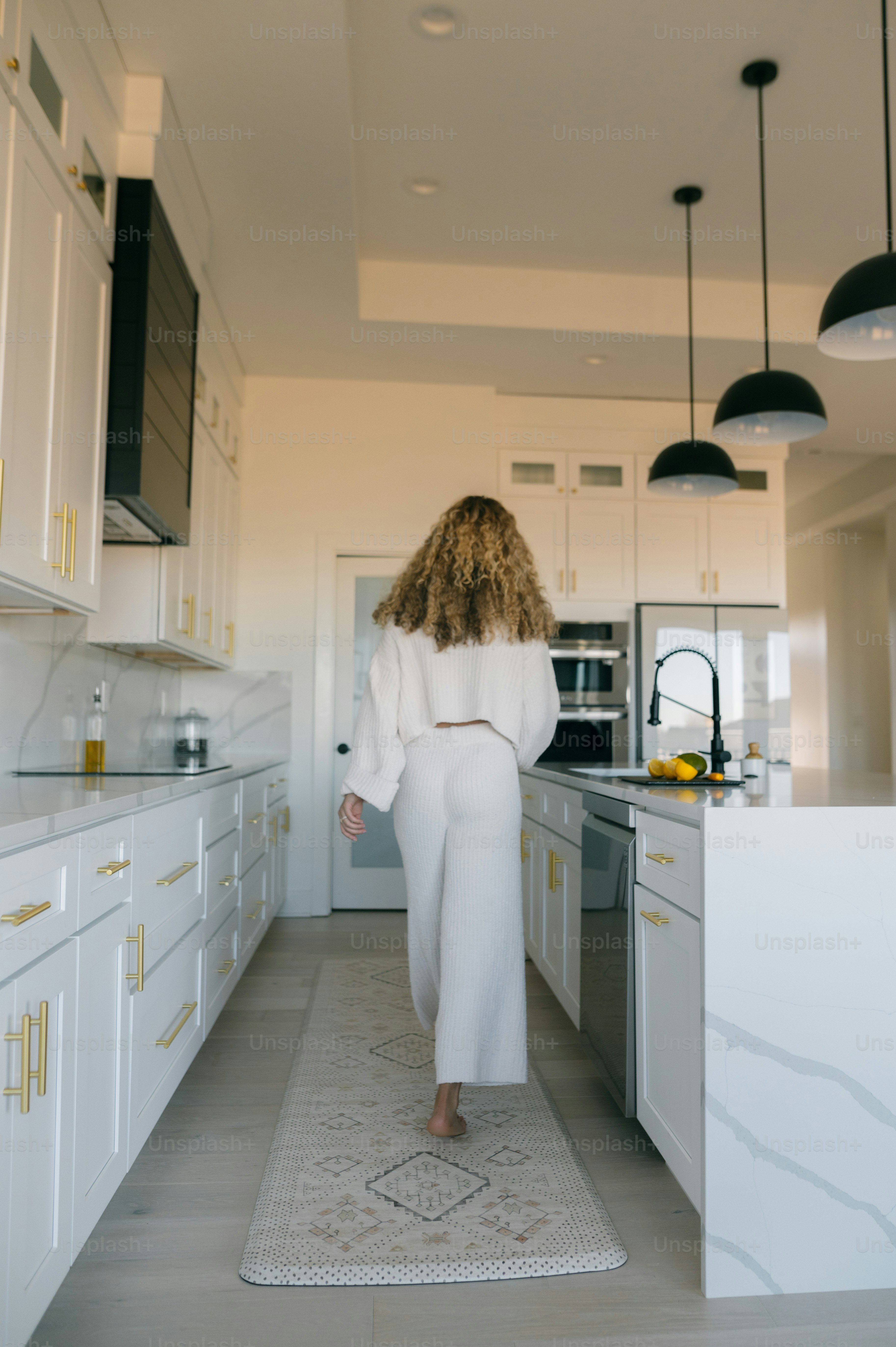 Une femme en robe blanche traverse une cuisine