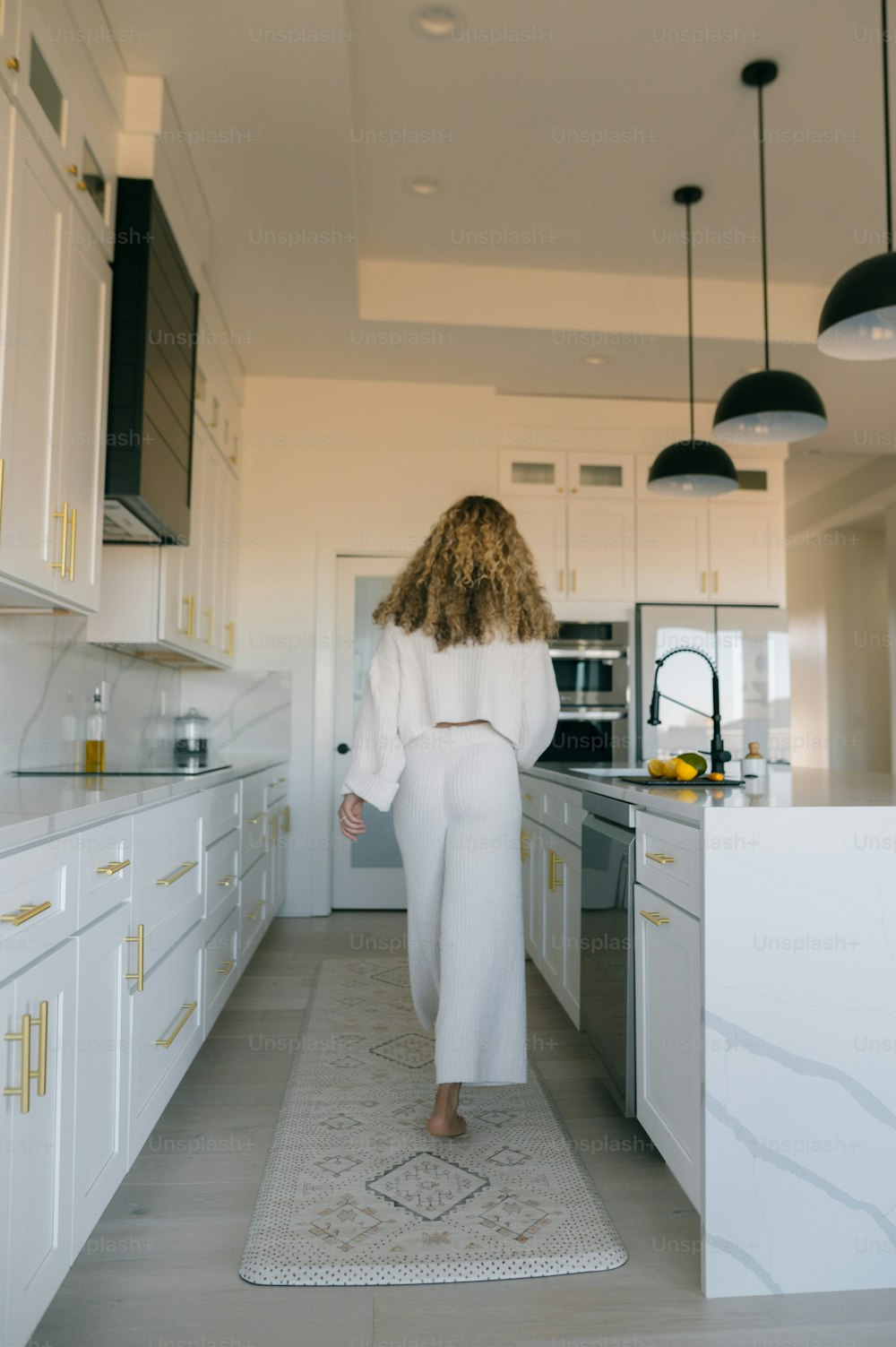 a woman in a white robe is walking through a kitchen