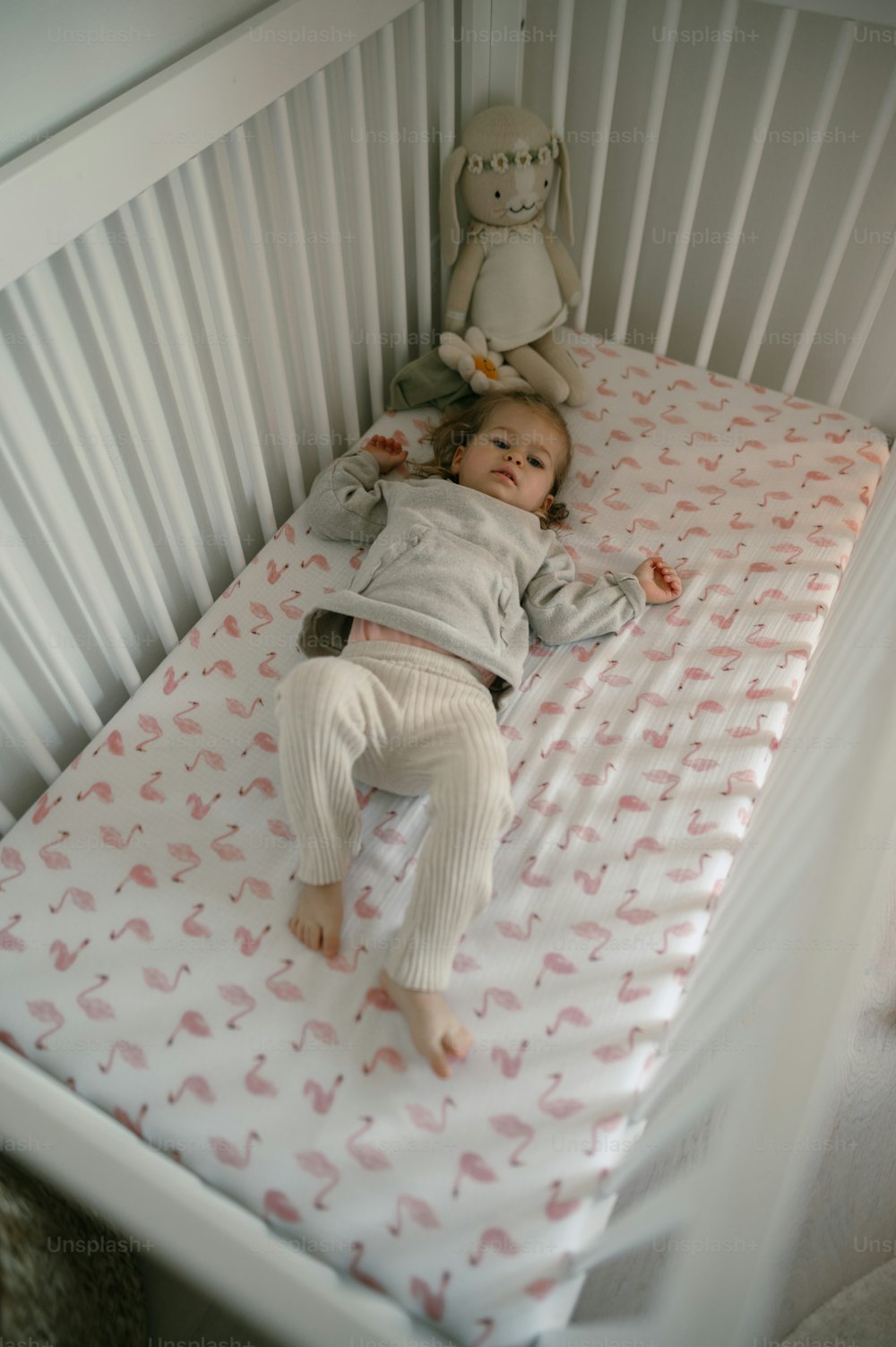 a baby laying in a crib with a stuffed animal