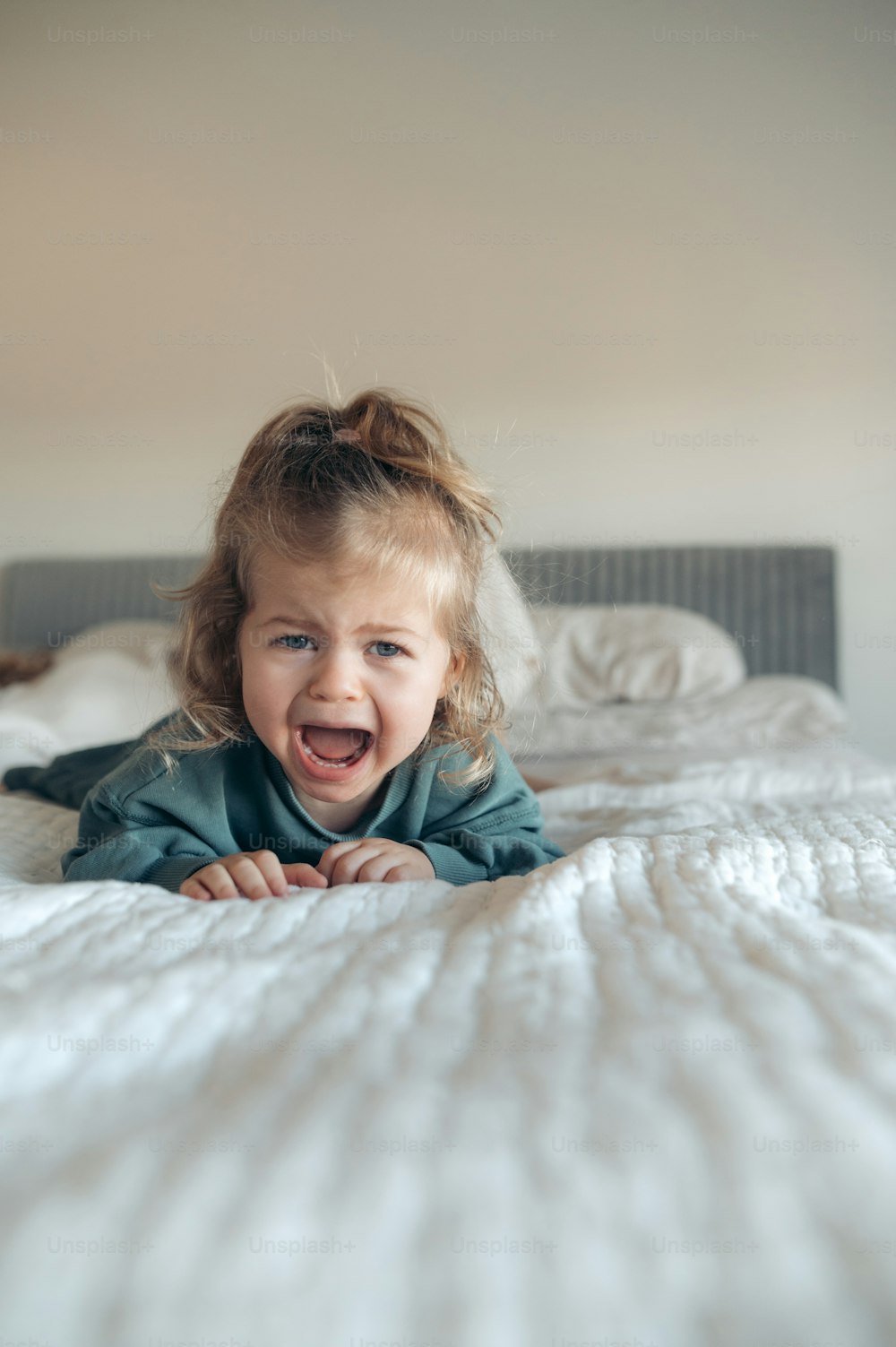 a little girl laying on top of a bed