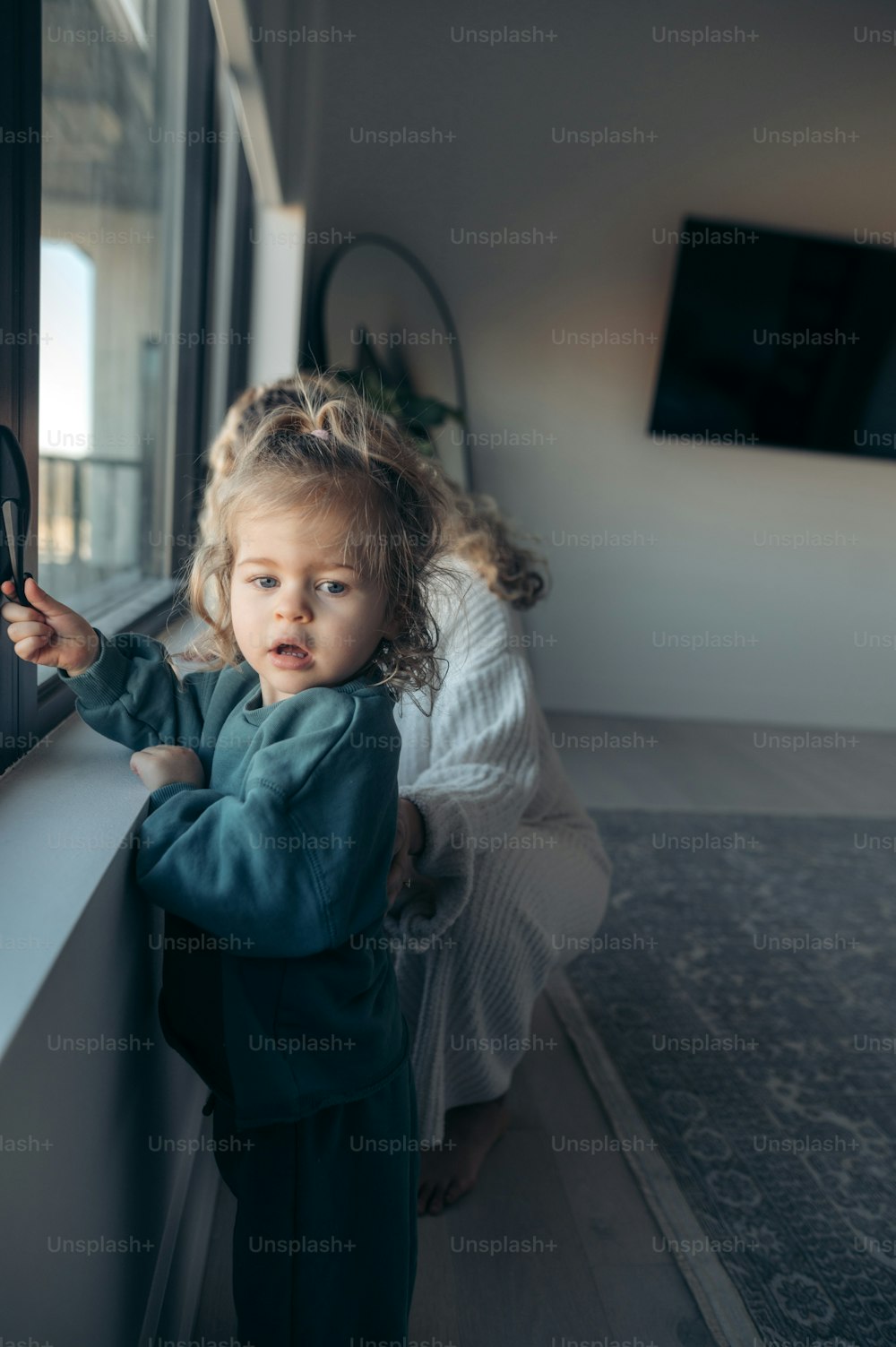 a little girl standing next to a window